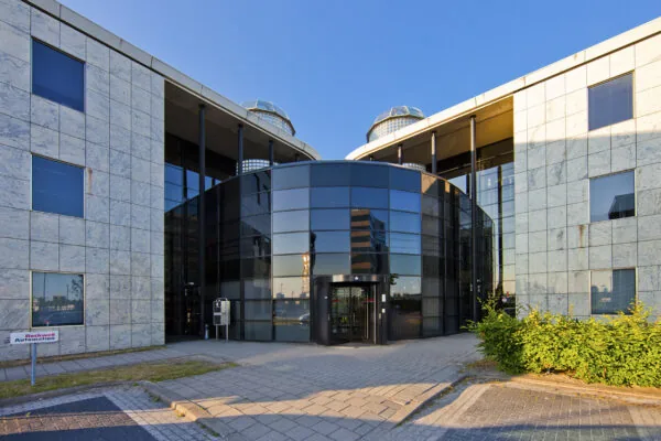 Vooraanzicht van een modern kantoorgebouw aan de Rivium 1e Straat met glazen entree en marmeren gevel.